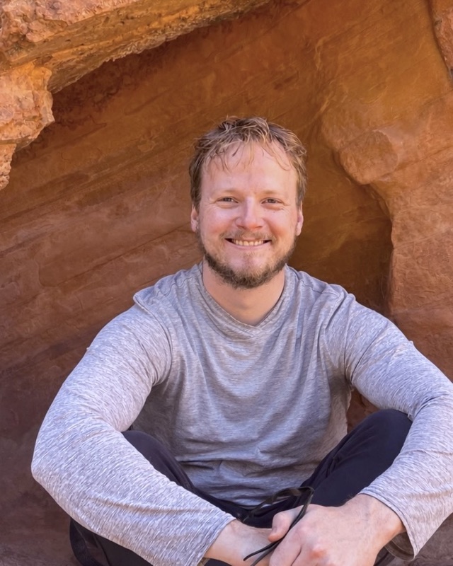 Joe Davison sitting in a sandstone alcove